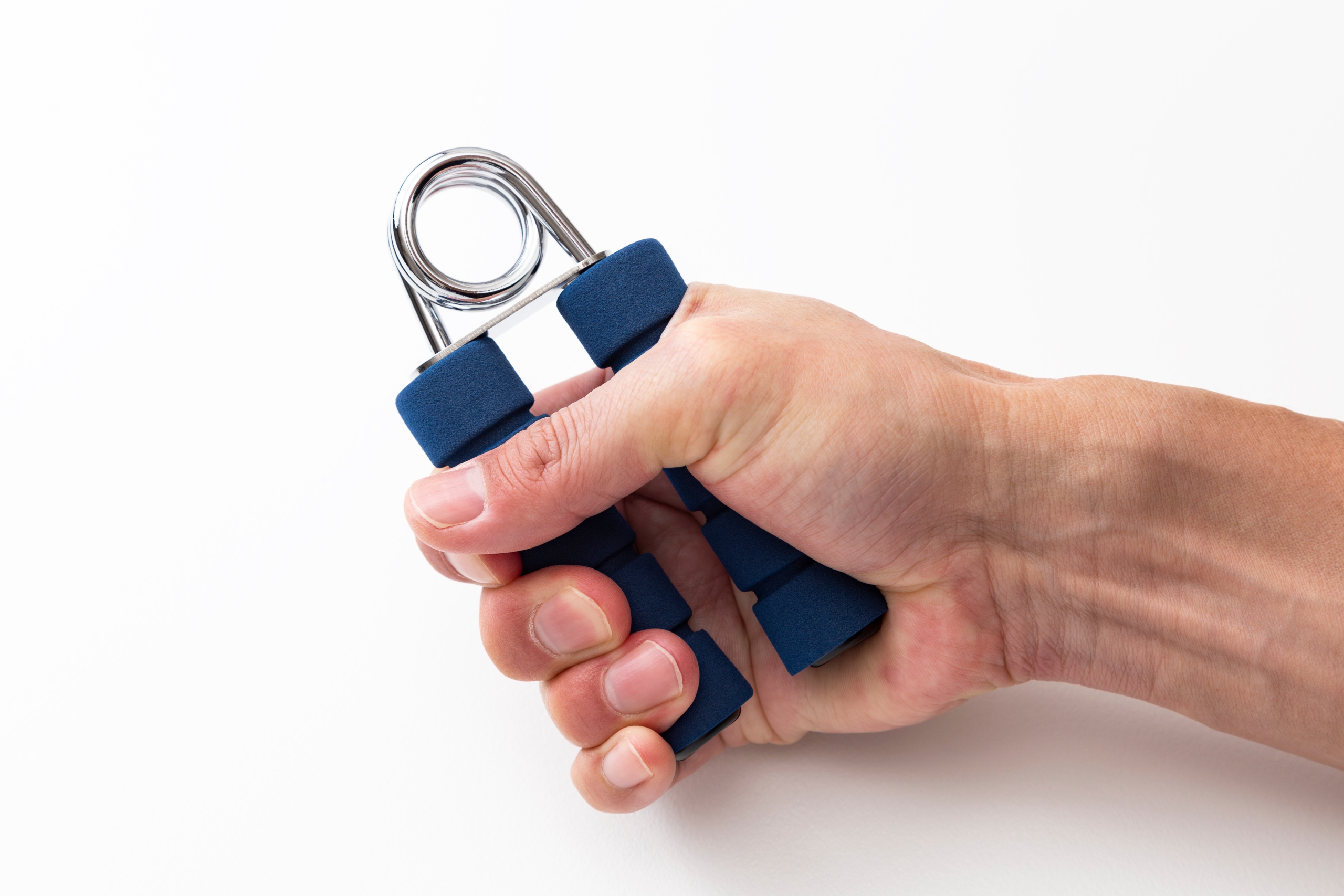 白い背景で、手が青いハンドグリッパーを握っている様子。握力強化や筋力トレーニングを示す。