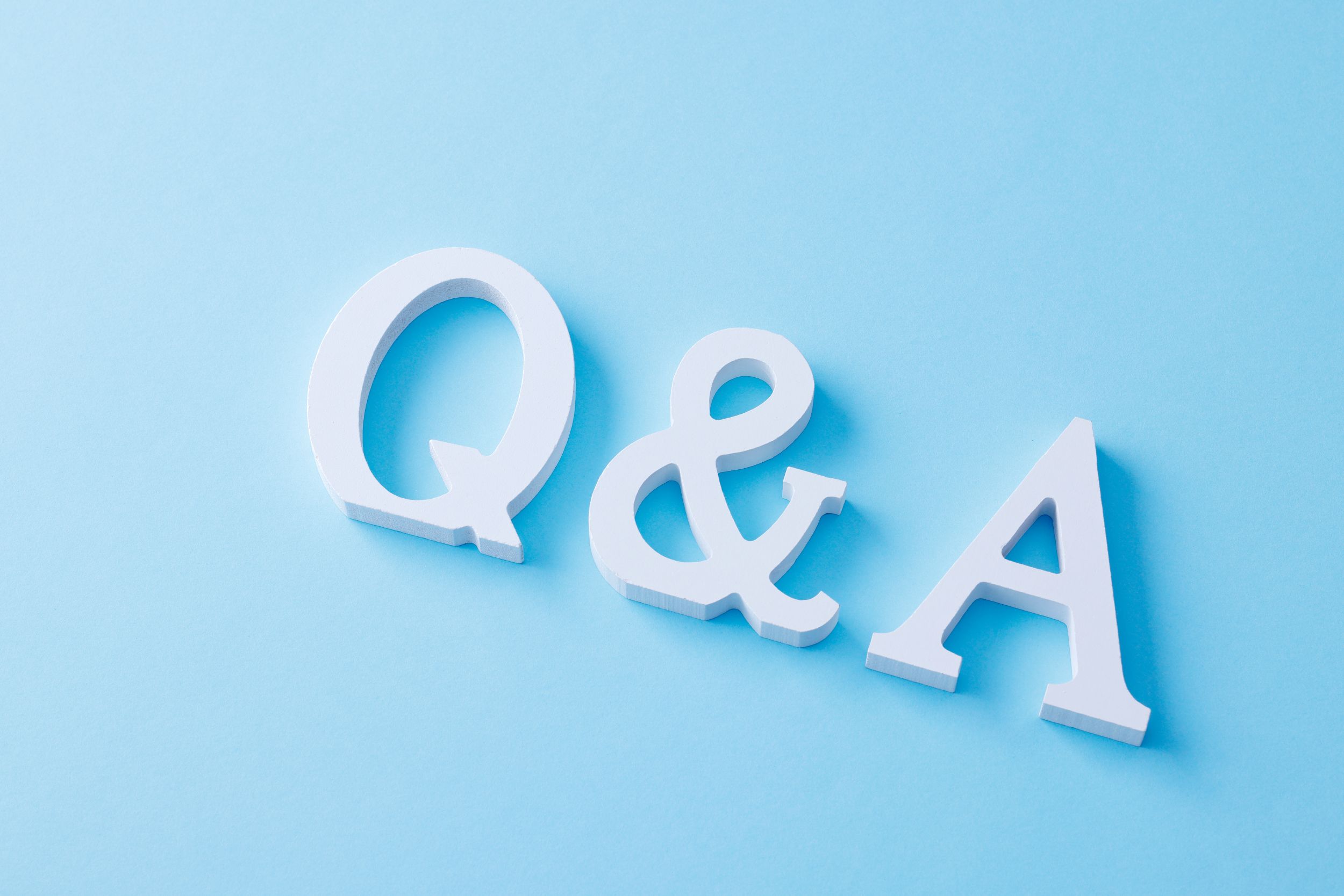 淡い水色の背景に白い立体の英字で「Q & A」が斜めに並んでいる